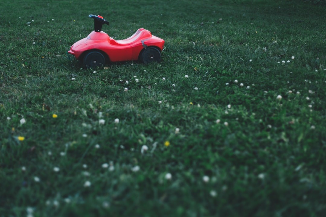red ride-on toy car on grass field
